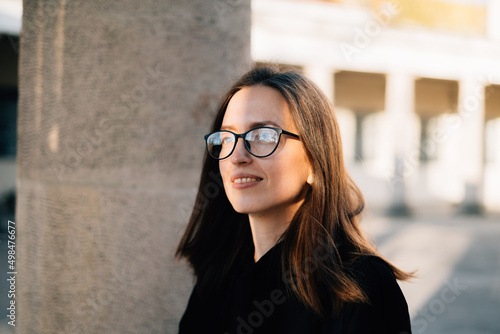 Smiling woman in eyeglasses admiring sunny street photo