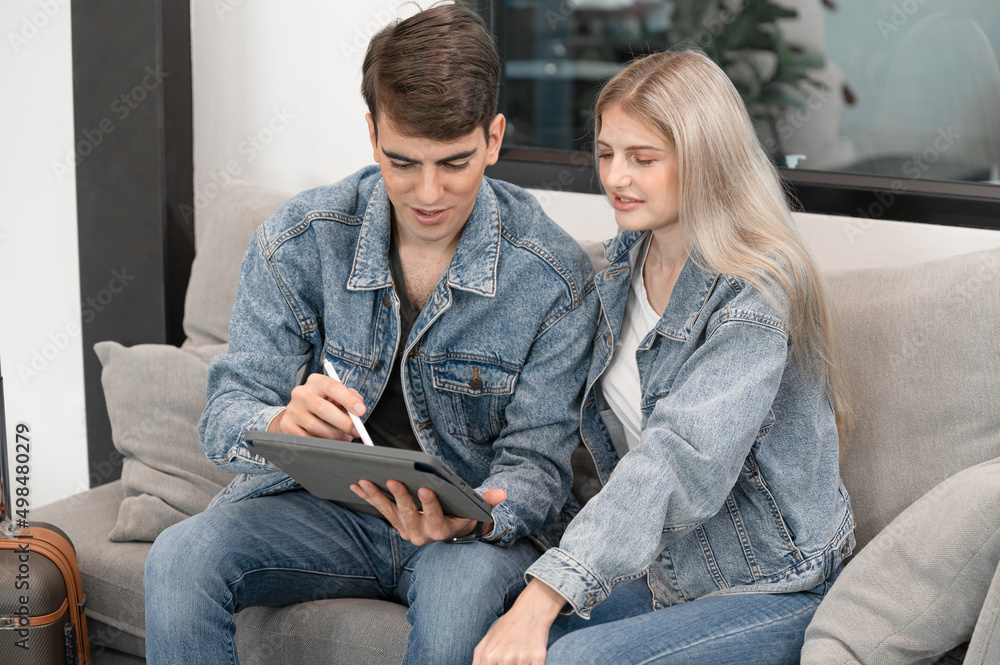 Happy man with girl friend play tablet at room in the airport Happy man with girl friend play tablet at room in the airport