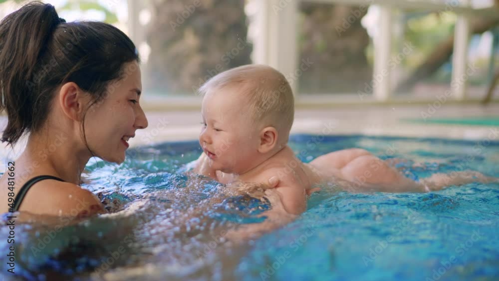 Happy mother in red swimming suit with baby son surfing water with fun in swimming pool. Healthy lifestyle, active parent, swimming lessons in indoor swimming pool with child, little fun kid on Happy mother in red swimming suit with baby son surfing water with fun in swimming pool. Healthy lifestyle, active parent, swimming lessons in indoor swimming pool with child, little fun kid on