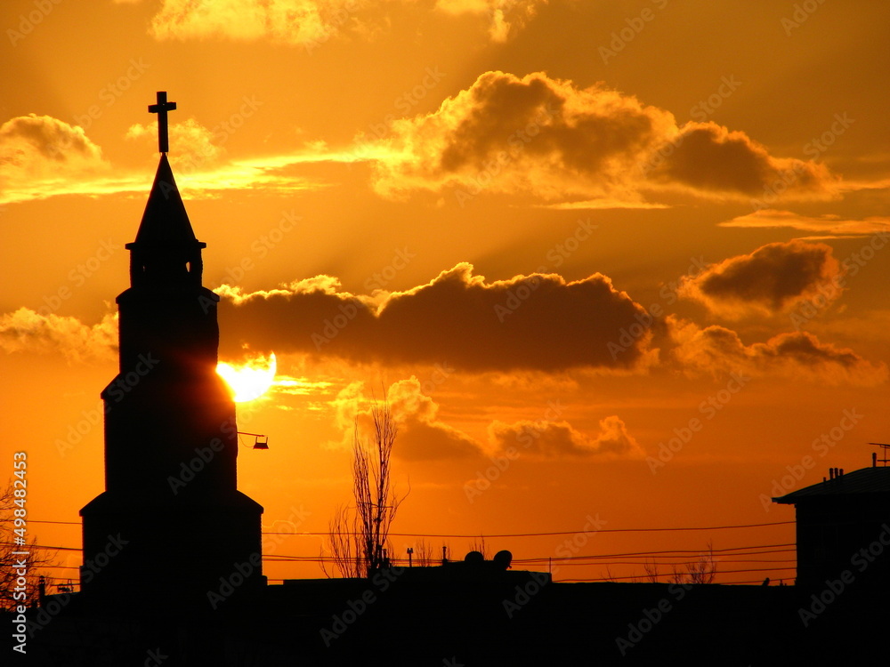 A church standing in front of a setting sun