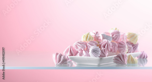 Homemade colorful meringue on a pink background.