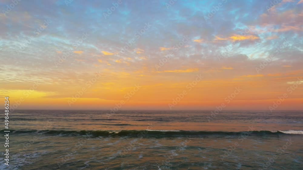 A vibrant golden sunset over the Pacific Ocean with the waves swelling and rolling to the beach A vibrant golden sunset over the Pacific Ocean with the waves swelling and rolling to the beach