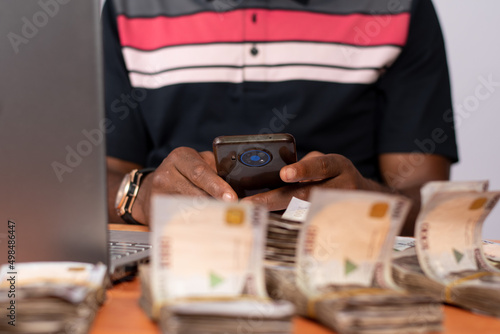 african businessman with plenty cash using phone and laptop
