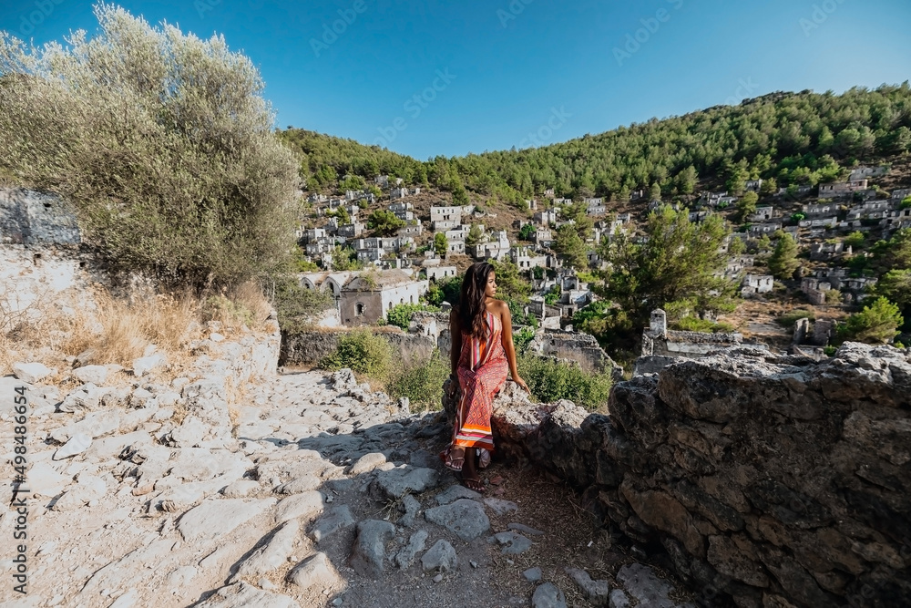 young asian female sitting on a rock staircase in kayakoy ghost town village in fethiye turkey at sunset