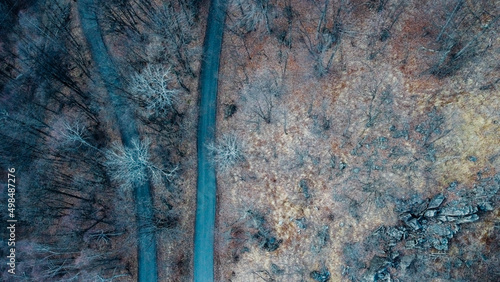 Aerial high angle view of narrow winding curvy mountain road among the trees in winter forest. Bird s eye view landscape.
