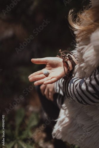Child's hand holding a wood snail shell. Happy childhood outdoor