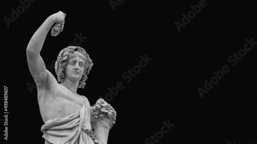 Paganism in Ancient Times. Roman or Greek god Bacchus holding grapes, a neoclassical marble statue, erected in the 19th century in Rome historic center (Black and white with copy space)