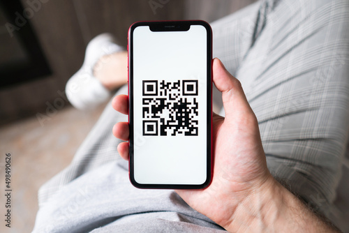 Young man in modern cafe showing smartphone scan QR code for payment 