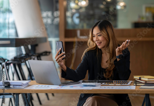 Asian businesswoman using smartphone for video call working at office desk © crizzystudio