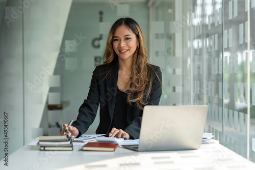 Asian businesswoman sitting working on laptop in office. tax, accounting, financial concept