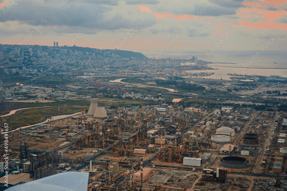 The cityscape of Haifa city and metropolitan area. Aerial Panoramic view from privat aircraft showing large industrial chimneys against houses and port and bay of Haifa Israel 