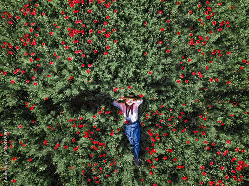 Aerial view from above Girl in straw hat in the red poppies field Papaveroideae in the spring  photo