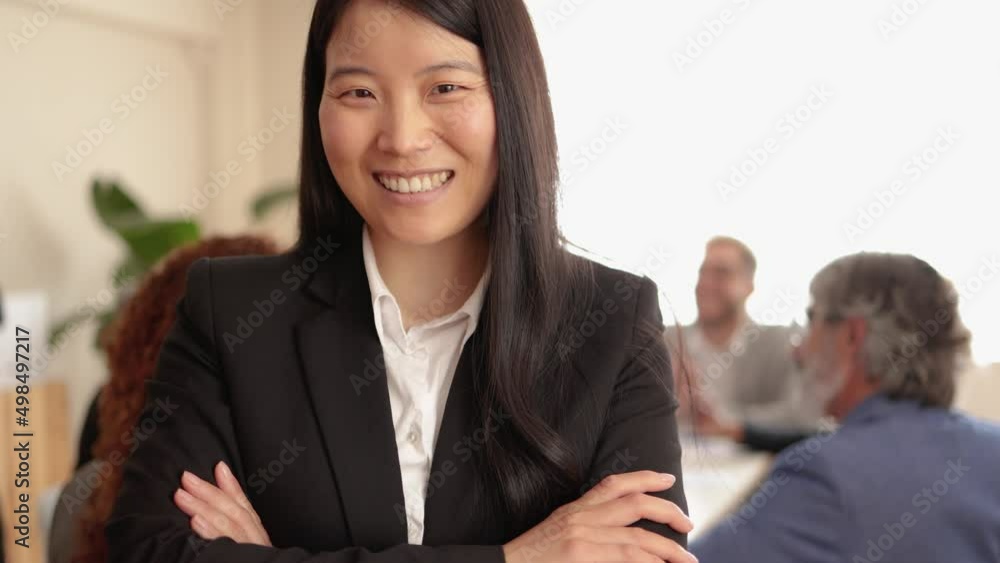 Asian woman smiling on camera while working with colleagues inside bank office Asian woman smiling on camera while working with colleagues inside bank office