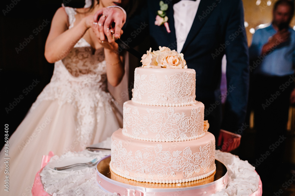 Bride and a groom is cutting their rustic wedding cake on wedding banquet. Newlyweds eating cake. Bride and a groom is cutting their rustic wedding cake on wedding banquet. Newlyweds eating cake.