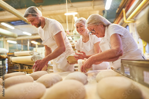 Obraz na płótnie Senior woman as a baker with a team baking a loaf of bread