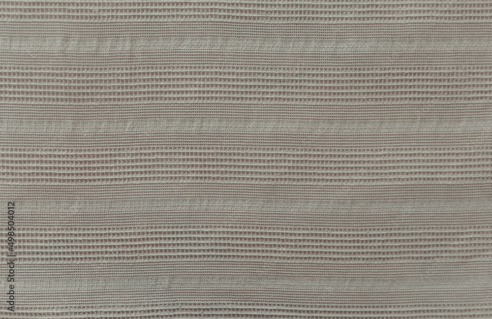 Linen blanket on a bed with vertical linear ornament. Beige fabric texture. Original textile background. Linen blanket on a bed with vertical linear ornament. Beige fabric texture. Original textile background.