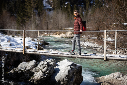 Mid Adult Woman Hiker Discovery Winter Nature Crossing a Suspended bridge 