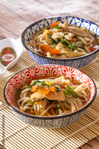 two bowls of thaï style noodle soup with chicken and vegetables, healthy food