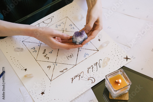 Woman holding crystals in her hands. Beautiful hand drawn natal chart.