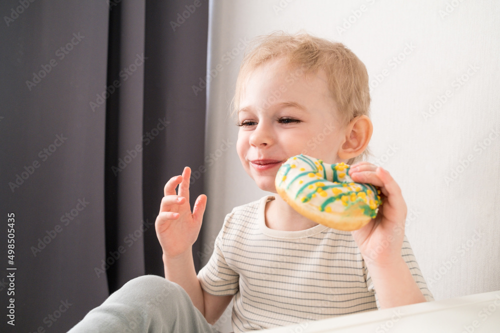 Toddler boy takes a bite of his donut. Toddler boy takes a bite of his donut.