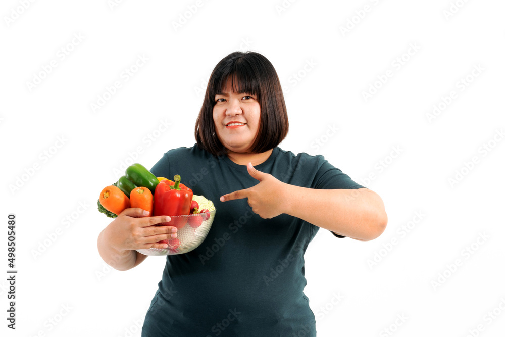 Portrait of a plump girl wearing a gray t-shirt holding fresh vegetables on a white background. Selective focus. Portrait of a plump girl wearing a gray t-shirt holding fresh vegetables on a white background. Selective focus.