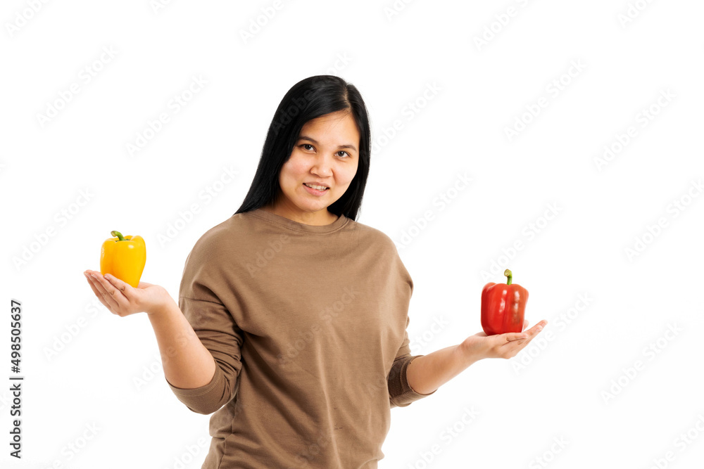 Portrait of a beautiful woman with long hair wearing a brown long-sleeve shirt holding colorful sweet peppers on a white background. Selective focus. Portrait of a beautiful woman with long hair wearing a brown long-sleeve shirt holding colorful sweet peppers on a white background. Selective focus.
