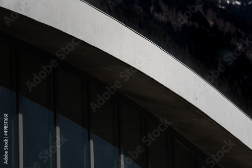 Architectural detail of sloping white concrete rooftop arch and facade