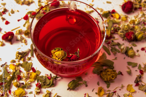 Tea in a glass cup with a rosebud on a background with herbal and flower tea