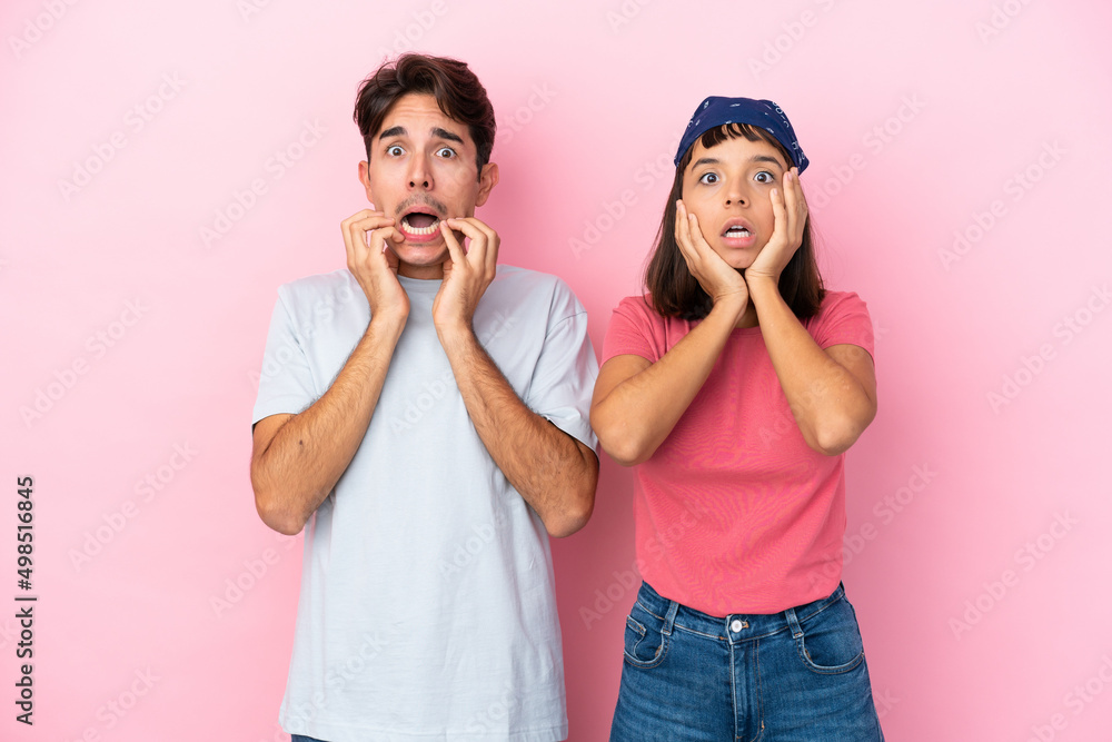 Young couple isolated on pink background surprised and shocked while looking right Young couple isolated on pink background surprised and shocked while looking right