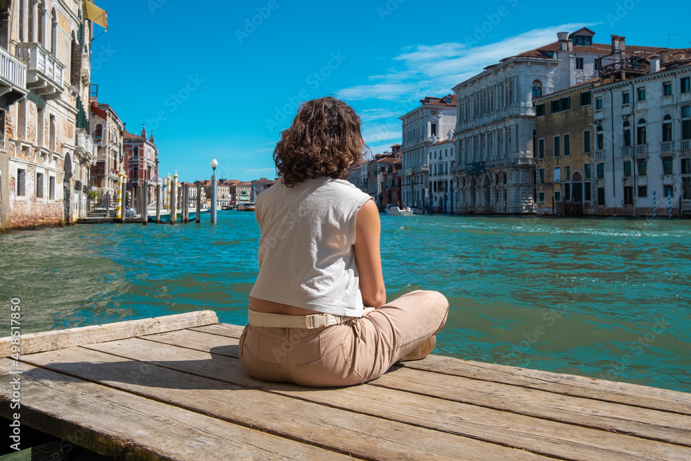 Young woman meditating facing the canals of Venice in Italy