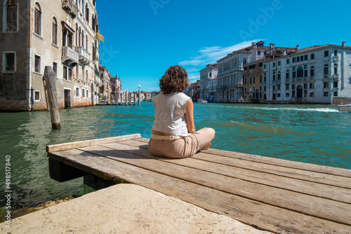 Young woman meditating facing the canals of Venice in Italy