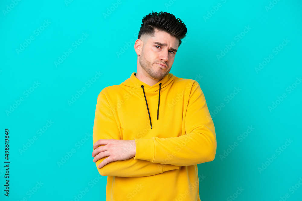 Young caucasian man isolated on blue background feeling upset