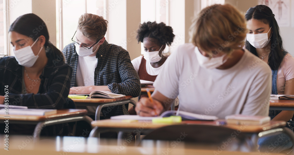 Nothing gets in their way of getting that grade. Shot of masked teenagers writing an exam in a classroom. Nothing gets in their way of getting that grade. Shot of masked teenagers writing an exam in a classroom.