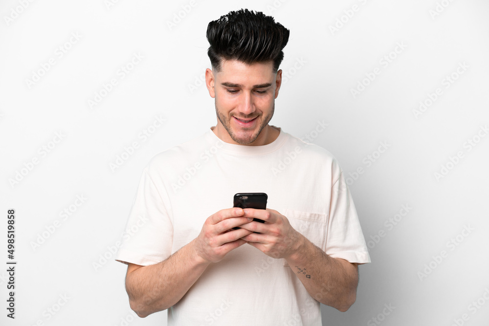 Young caucasian man isolated on white background sending a message or email with the mobile Young caucasian man isolated on white background sending a message or email with the mobile