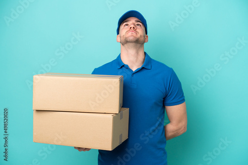 Delivery caucasian man isolated on blue background and looking up