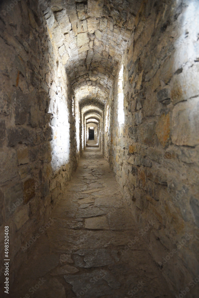 To see the light at the end of the tunnel, hope. A long brick aisle, hallway with the sun light inside a medieval castle.