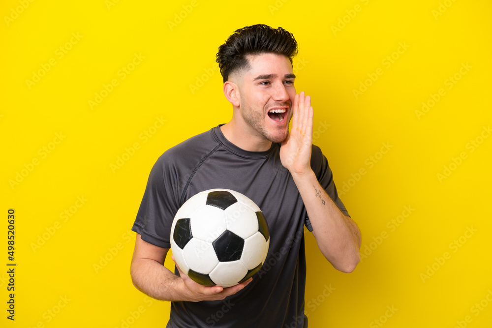 Handsome young football player man isolated on yellow background shouting with mouth wide open to the side Handsome young football player man isolated on yellow background shouting with mouth wide open to the side