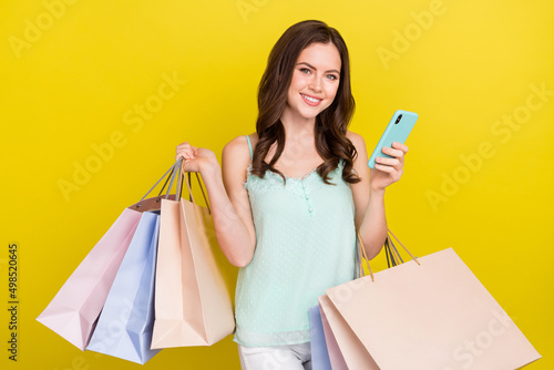 Photo of charming attractive girl in trendy outfit buy clothes online surfing eshop isolated on yellow color background
