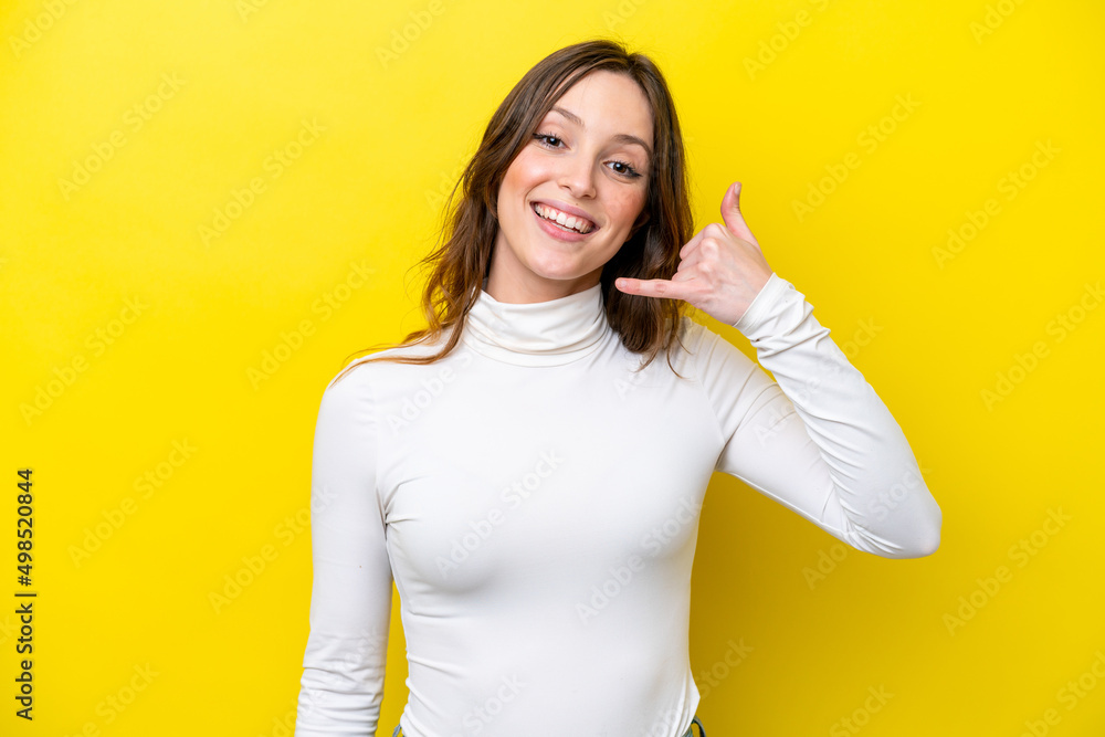Young caucasian woman isolated on yellow background making phone gesture. Call me back sign Young caucasian woman isolated on yellow background making phone gesture. Call me back sign