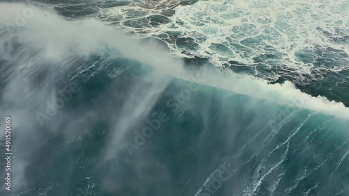 Aerial top down view of huge storm wave crashing on the Atlantic coast. Flying on big wave surf in stormy weather with strong wind. Slow motion, 4K