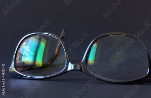 Anti-glare coating on the glasses. Glasses with black frames on a dark background. © Tula L