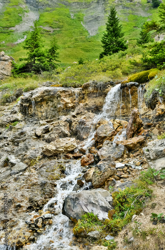 Beautiful Alpine summer landscape with small refreshing waterfall in area of Saint-Guerin lake in Savoie, France. Eco planet background.