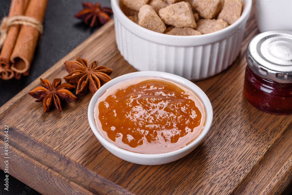 Delicious apricot jam, milk and sugar on a wooden cutting board Delicious apricot jam, milk and sugar on a wooden cutting board