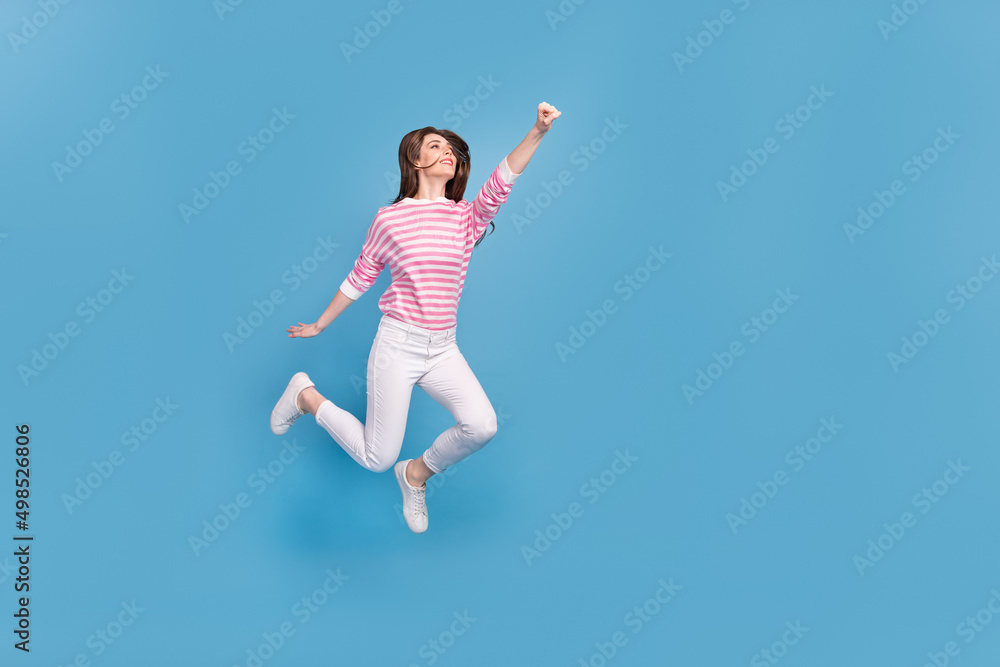 Full length profile portrait of active excited lady raise fist look empty space isolated on blue color background