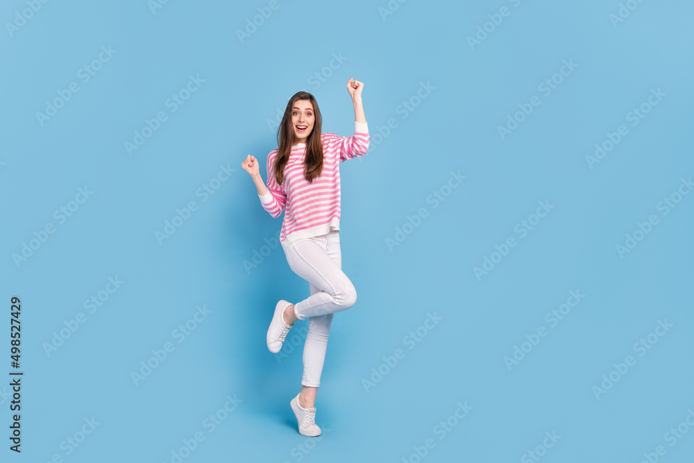 Full size photo of astonished positive lady raise fists triumph shout yeah isolated on blue color background