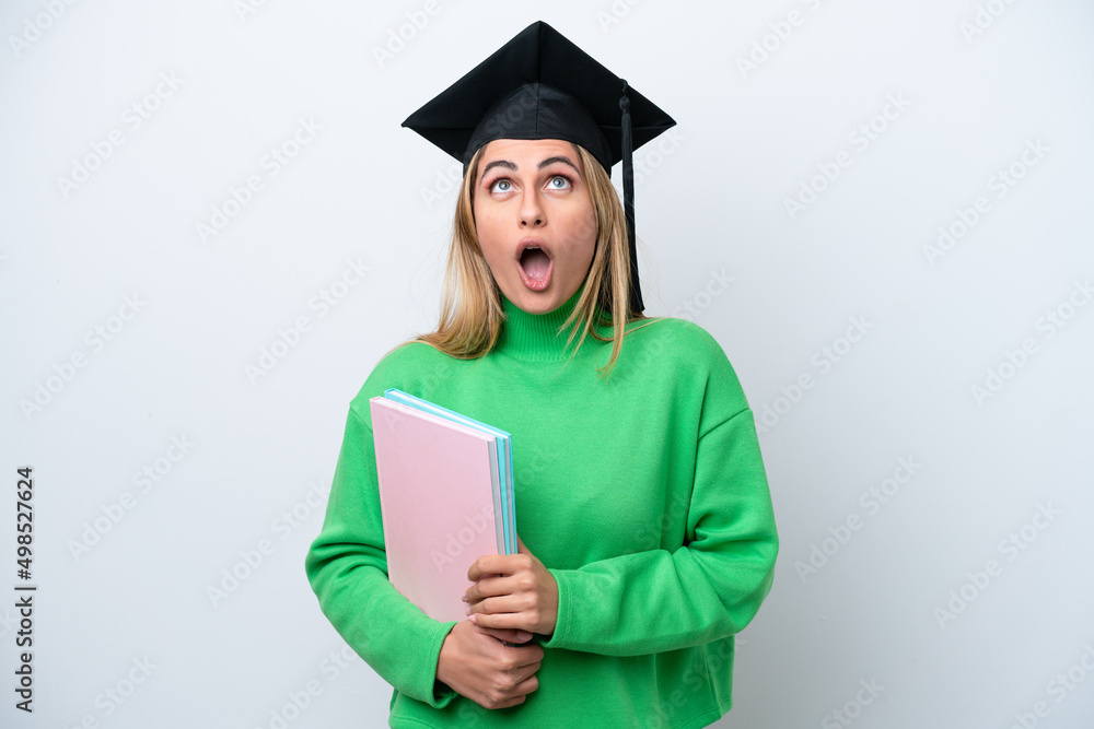Young university graduate woman isolated on white background looking up and with surprised expression Young university graduate woman isolated on white background looking up and with surprised expression