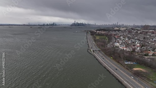 Wallpaper Mural An aerial view high over the waters of Upper Bay in Brooklyn NY. The drone camera dolly in and boom down to the Belt Parkway with the New York City skyline in the background on a cloudy evening. Torontodigital.ca
