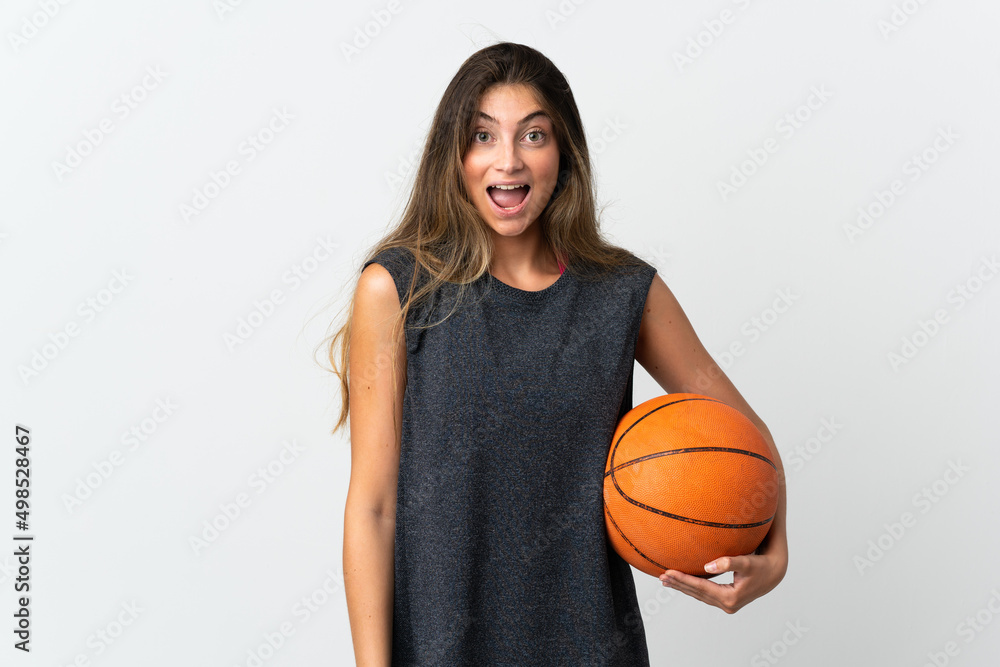 Young woman playing basketball isolated on white background with surprise facial expression