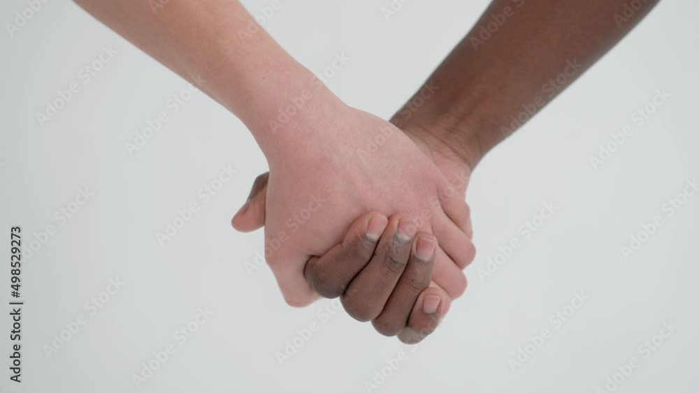 Caucasian woman and african american man holding hands. Close-up. The concept of racial unity and friendship of peoples Caucasian woman and african american man holding hands. Close-up. The concept of racial unity and friendship of peoples