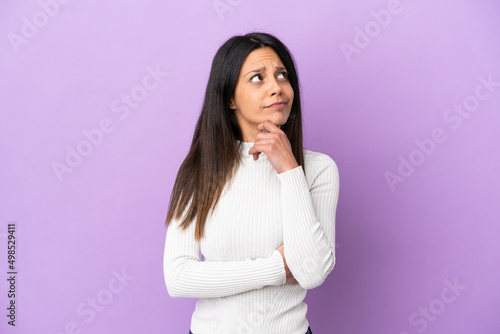 Young caucasian woman isolated on purple background having doubts © luismolinero